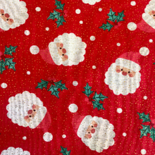 Christmas-themed fabric pattern with Santa Claus, holly leaves, and snowflakes on a red background.